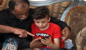 Hussein Dawabsha (L) sits with his grandson Ahmed, the survivor of the arson attack that killed his parents and 18-month-old brother, as they look at images on a phone at their home in the Israeli occupied West Bank village of Duma on May 18, 2020, after an Israeli court convicted a Jewish settler on three counts of murder over a 2015 arson attack. - Amiram Ben-Uliel, 25, from the West Bank settlement of Shilo, was also found guilty of two counts each of attempted murder and arson, along with conspiracy to commit a hate crime, a court statement said. (Photo by JAAFAR ASHTIYEH / AFP) (Photo by JAAFAR ASHTIYEH/AFP via Getty Images)