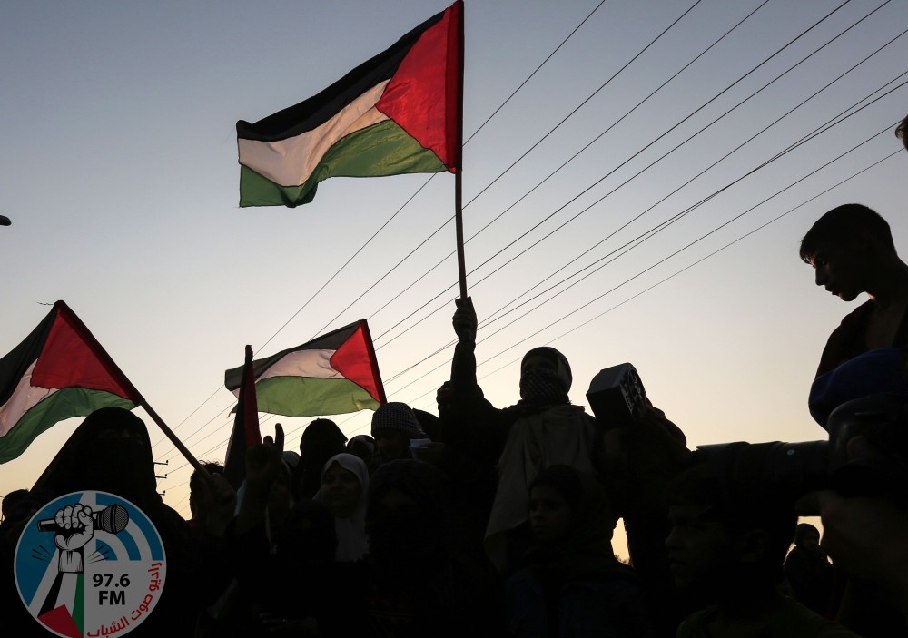 TOPSHOT - Palestinian protesters wave their national flags at sunset during a demonstration near the Erez crossing with Israel on September 4, 2018, in the northern Gaza Strip protesting against the United States decision to stop funding and backing the United Nations agency for Palestinian refugees(UNRWA). (Photo by MAHMUD HAMS / AFP)