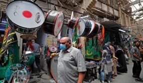 Iraqis pass by a store displaying religious banners amidst preparations ahead of the start of Muharram, in central Baghdad on August 8, 2021. Shiite Muslims over the world observe Muharram, the first Islamic month of the lunar calendar, to mark the seventh-century slaying of Prophet Mohammed's grandson Imam Hussein in Karbala. (Photo by AHMAD AL-RUBAYE / AFP)