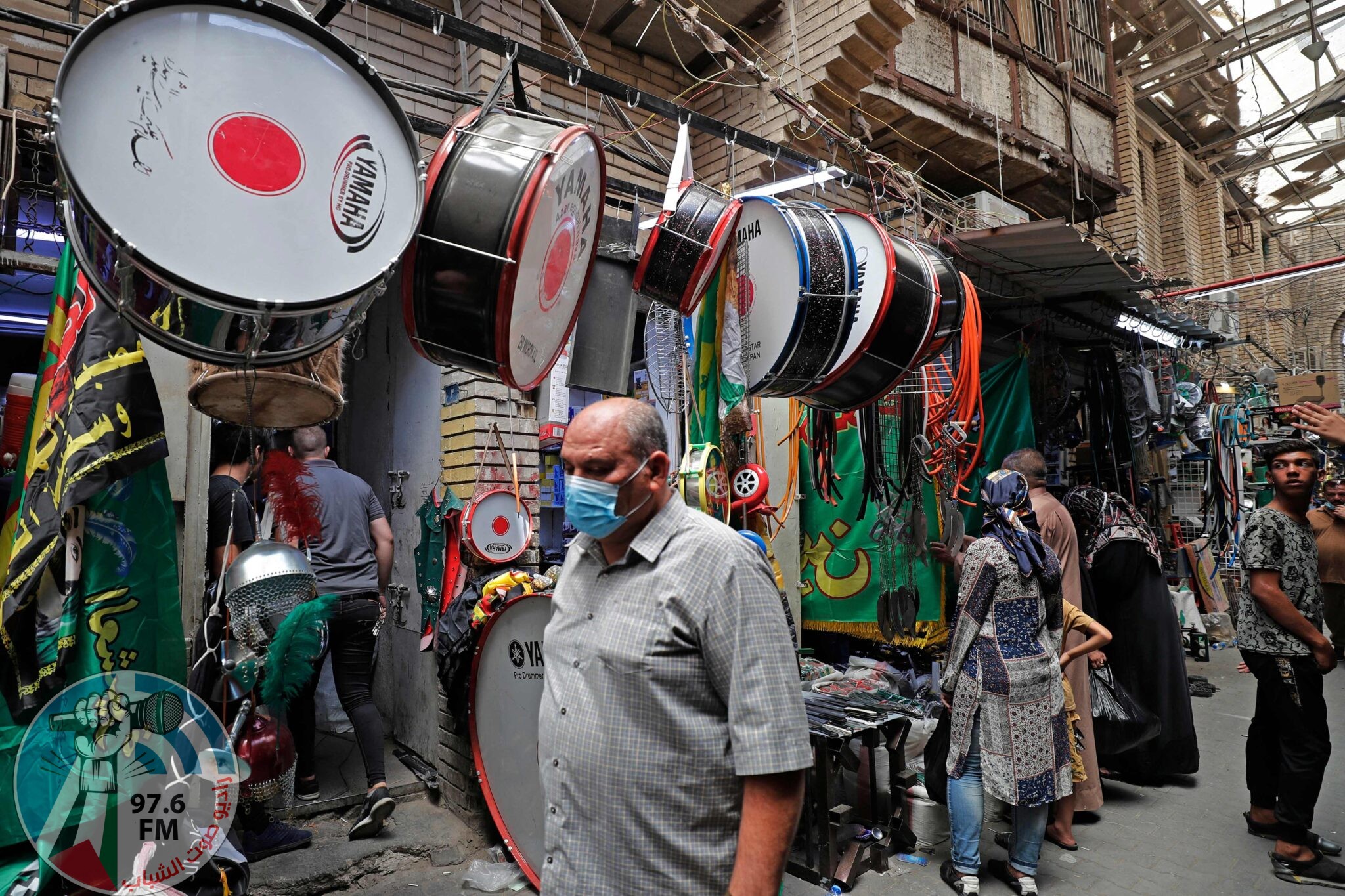 Iraqis pass by a store displaying religious banners amidst preparations ahead of the start of Muharram, in central Baghdad on August 8, 2021. Shiite Muslims over the world observe Muharram, the first Islamic month of the lunar calendar, to mark the seventh-century slaying of Prophet Mohammed's grandson Imam Hussein in Karbala. (Photo by AHMAD AL-RUBAYE / AFP)