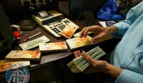 A Palestinian man counts stacks of banknotes at a currency exchange counter in the West Bank city of Ramallah on October 5, 2021. Palestinian businesses flush with too much Israeli cash, much of it brought in by the tens of thousands of Palestinians who work inside Israel or Jewish settlements in the West Bank, but experts say the buildup of hard currency risks stifling the Palestian financial system. (Photo by ABBAS MOMANI / AFP)