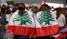 (FILES) In this file photo taken on October 27, 2019, Lebanese protesters wrapped in their national flag take part in a human chain along the coast from north to south as a symbol of unity during ongoing anti-government demonstrations in the area of Jal al-Dib in the northern outskirts of the Lebanese capital Beirut. Two years after a now-defunct protest movement shook Lebanon, opposition activists are hoping parliamentary polls will challenge the ruling elite's stranglehold on the country. (Photo by Patrick BAZ / AFP)