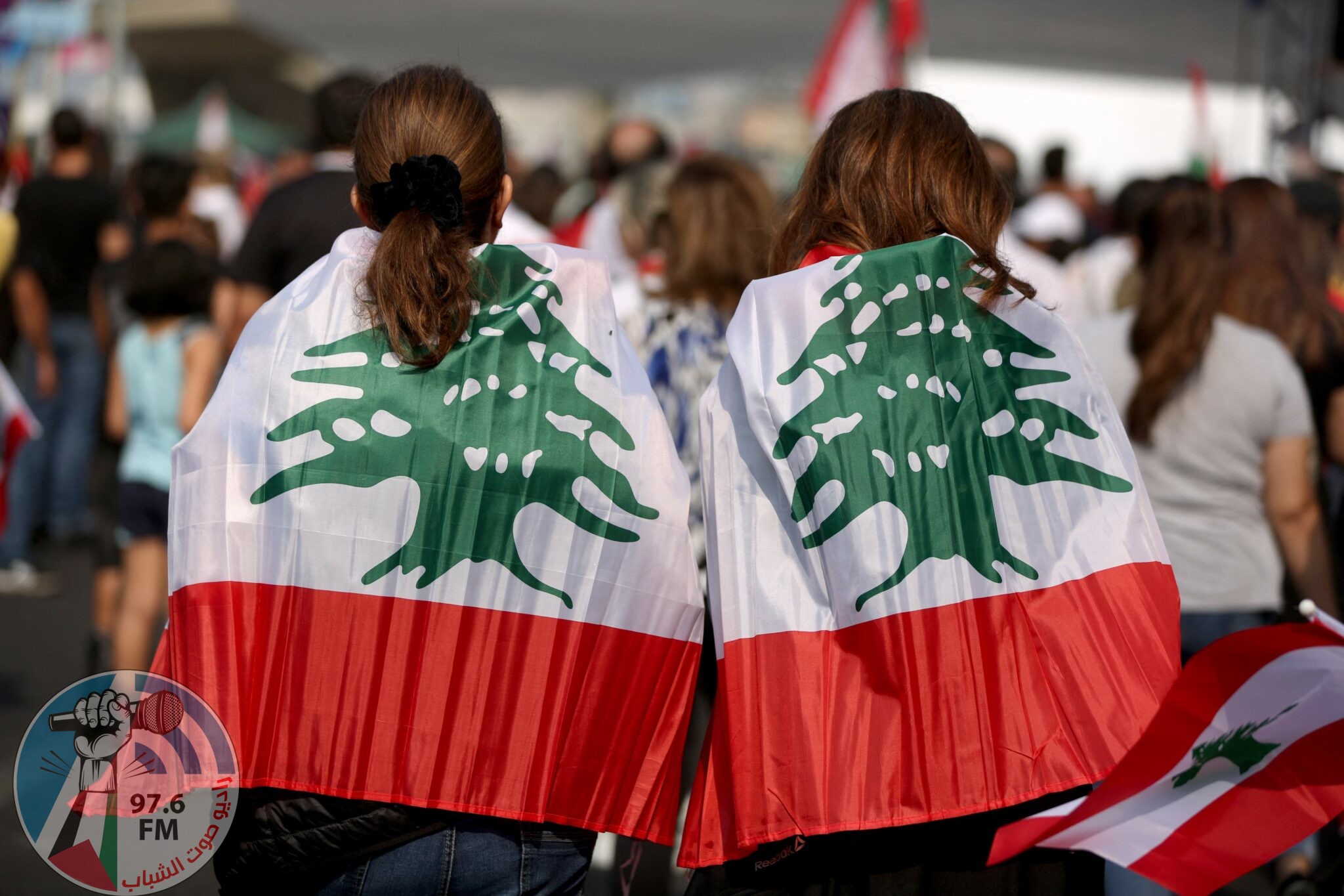 (FILES) In this file photo taken on October 27, 2019, Lebanese protesters wrapped in their national flag take part in a human chain along the coast from north to south as a symbol of unity during ongoing anti-government demonstrations in the area of Jal al-Dib in the northern outskirts of the Lebanese capital Beirut. Two years after a now-defunct protest movement shook Lebanon, opposition activists are hoping parliamentary polls will challenge the ruling elite's stranglehold on the country. (Photo by Patrick BAZ / AFP)