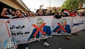 Iraqi demonstrators lift banners against Prime Minister Mustafa Al-Kadhimi during a protest rejecting last month's election result, near an entrance to the Green Zone in Baghdad on November 5, 2021. Hundreds of supporters of pro-Iran groups clashed with security forces in Iraq's capital, expressing their fury over last month's election result, AFP journalists and a security source said. (Photo by Ahmad AL-RUBAYE / AFP)