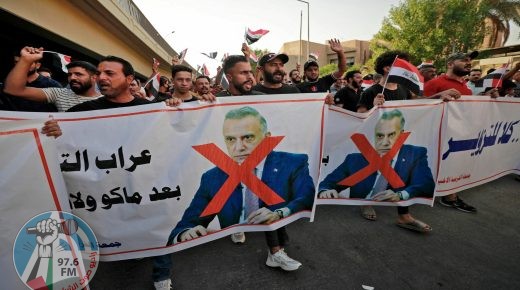 Iraqi demonstrators lift banners against Prime Minister Mustafa Al-Kadhimi during a protest rejecting last month's election result, near an entrance to the Green Zone in Baghdad on November 5, 2021. Hundreds of supporters of pro-Iran groups clashed with security forces in Iraq's capital, expressing their fury over last month's election result, AFP journalists and a security source said. (Photo by Ahmad AL-RUBAYE / AFP)