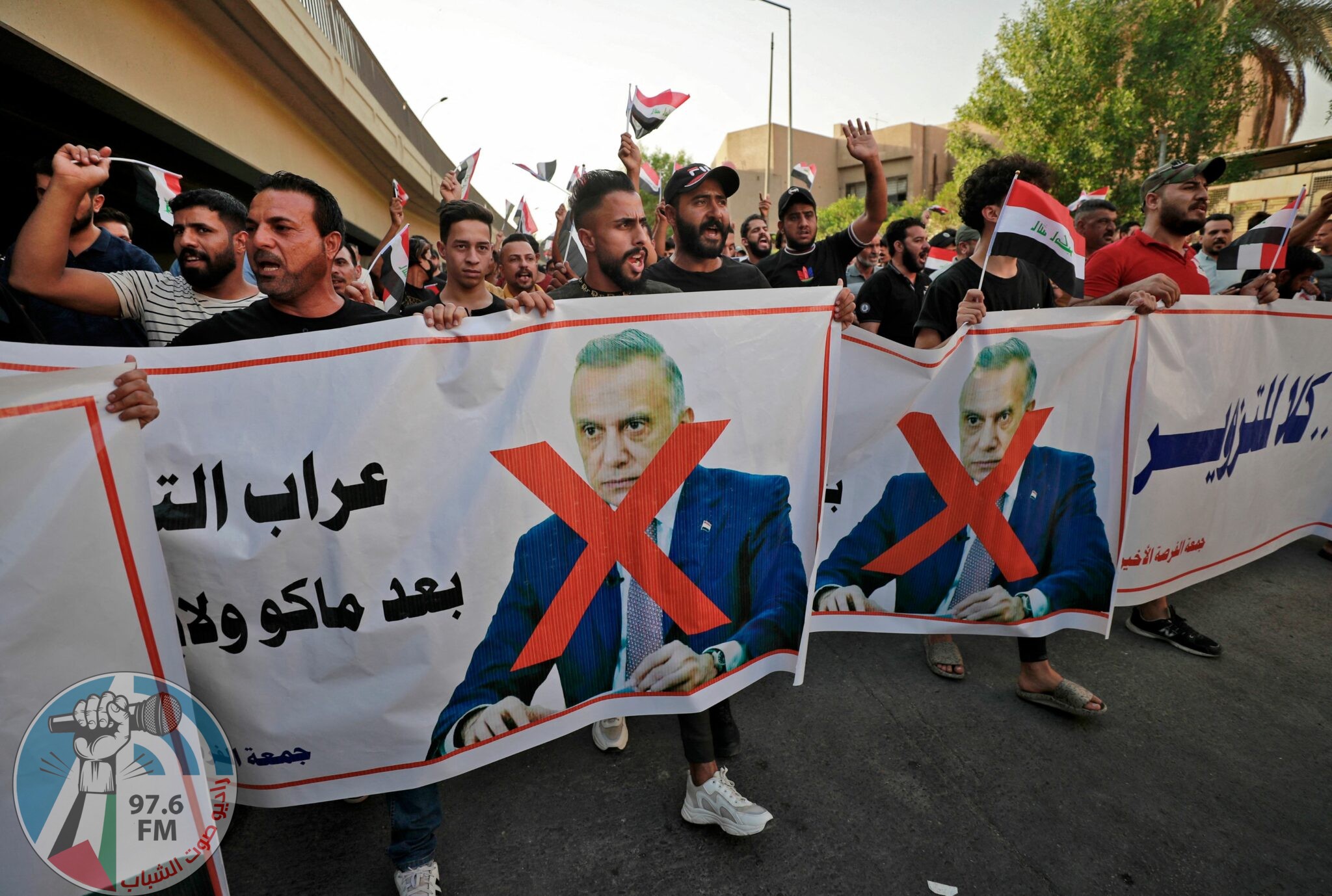 Iraqi demonstrators lift banners against Prime Minister Mustafa Al-Kadhimi during a protest rejecting last month's election result, near an entrance to the Green Zone in Baghdad on November 5, 2021. Hundreds of supporters of pro-Iran groups clashed with security forces in Iraq's capital, expressing their fury over last month's election result, AFP journalists and a security source said. (Photo by Ahmad AL-RUBAYE / AFP)