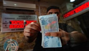 (FILES) In this file photo taken on August 6, 2020 a currency exchange office worker counts Turkish Lira banknotes in front of the electronic panel displaying currency exchange rates at an exchange office in Istanbul as Turkey's lira set a new record low against the US dollar. Turkey lira on November 23, 2021 has crashed 13% vs US dollar to new record low, AFP reports. (Photo by Yasin AKGUL / AFP)