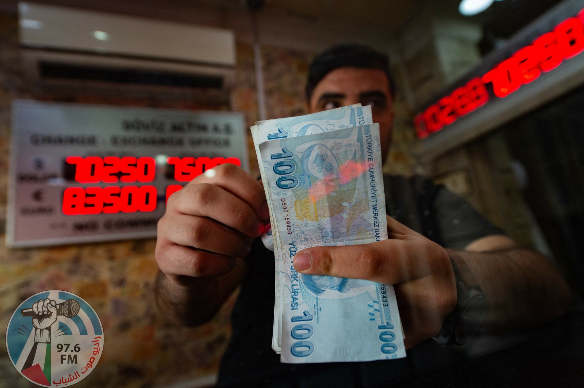 (FILES) In this file photo taken on August 6, 2020 a currency exchange office worker counts Turkish Lira banknotes in front of the electronic panel displaying currency exchange rates at an exchange office in Istanbul as Turkey's lira set a new record low against the US dollar. Turkey lira on November 23, 2021 has crashed 13% vs US dollar to new record low, AFP reports. (Photo by Yasin AKGUL / AFP)