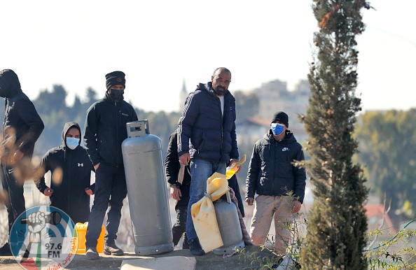 Palestinian men hold a gas tank on the roof of a house as Israeli police prepare to evict a family from the same building on January 17, 2022 in Jerusalem's east district of Sheikh Jarrah. (Photo by Ahmad GHARABLI / AFP) (Photo by AHMAD GHARABLI/AFP via Getty Images)