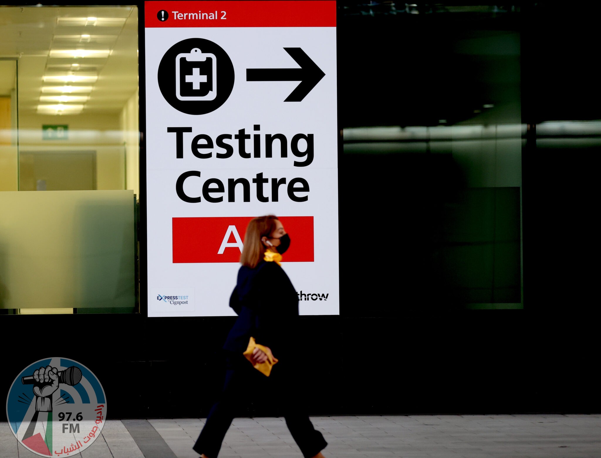 (211201) -- LONDON, Dec. 1, 2021 (Xinhua) -- A passenger walks past a placard indicating the testing center in Heathrow Airport in London, Britain, Nov. 30, 2021. British Prime Minister Boris Johnson said Saturday all travellers entering Britain must take a PCR test by the end of the second day after their arrival, and must self-isolate until they receive a negative test result. Passengers arriving in Britain from countries in Britain's travel "red list", including South Africa, from 0400 GMT on Nov. 28 will be required to book and pay for a government-approved hotel to quarantine for 10 days. Omicron, a new COVID-19 variant, has been detected in a growing number of countries and regions worldwide, prompting governments to tighten their restrictions and impose new travel bans. (Xinhua/Li Ying)