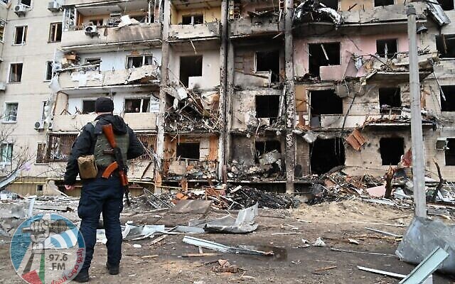 A police officer stands guard at a damaged residential building at Koshytsa Street, a suburb of the Ukrainian capital Kyiv, where a military shell allegedly hit, on February 25, 2022. - Invading Russian forces pressed deep into Ukraine as deadly battles reached the outskirts of Kyiv, with explosions heard in the capital early Friday that the besieged government described as "horrific rocket strikes". The blasts in Kyiv set off a second day of violence after Russian President Vladimir Putin defied Western warnings to unleash a full-scale ground invasion and air assault that quickly claimed dozens of lives and displaced at least 100,000 people. (Photo by GENYA SAVILOV / AFP)